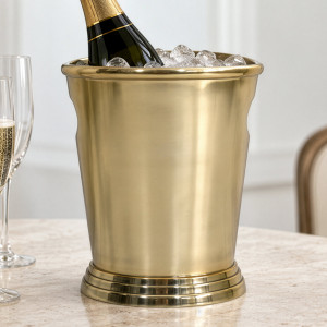 Gold champagne bucket with a stepped base holding a bottle in ice beside champagne flutes