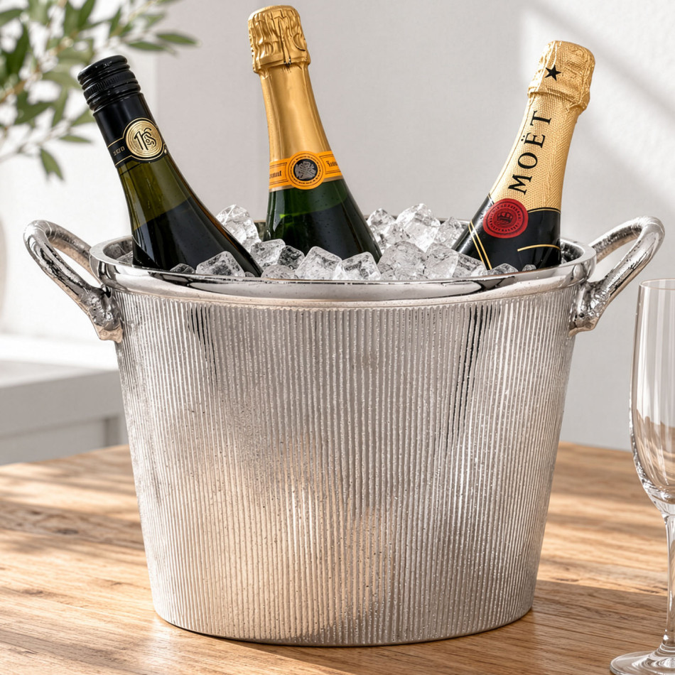 Ribbed silver champagne bucket filled with ice and three bottles on a wooden table