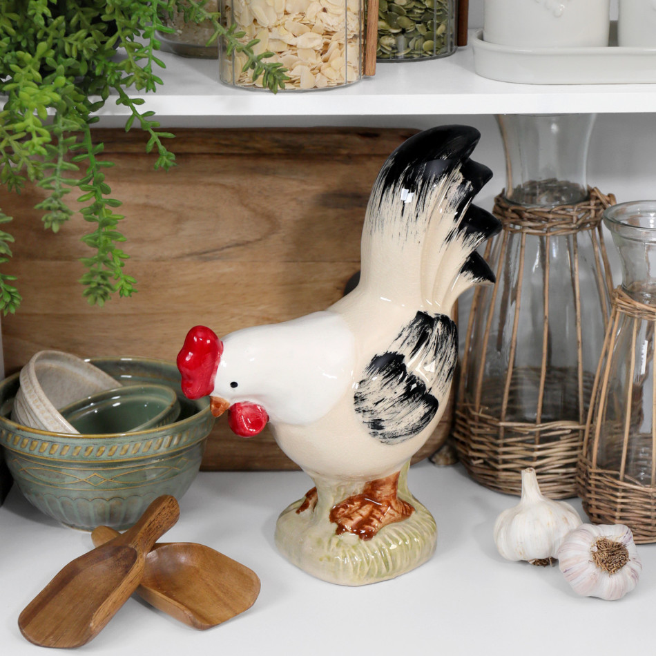 Ceramic rooster decor styled on a white kitchen bench with bowls, wicker-covered jugs, garlic and wooden scoops.