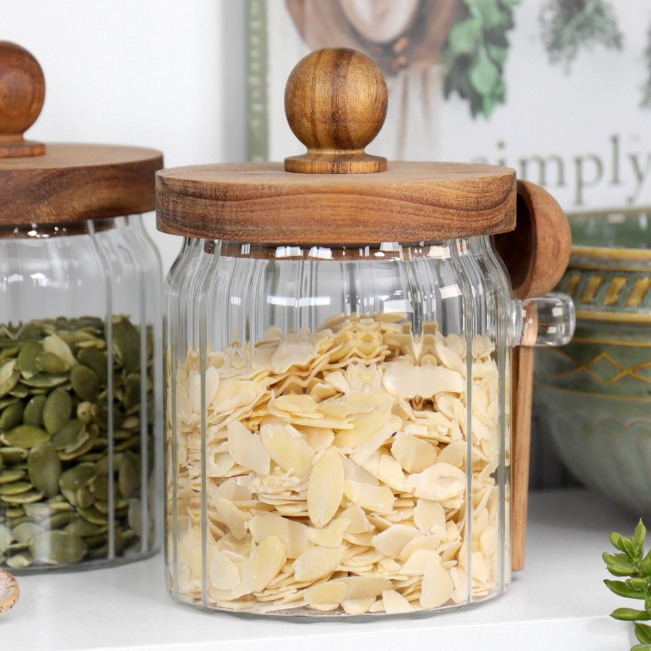 Ribbed glass storage jar with wooden lid and spoon filled with flaked almonds
