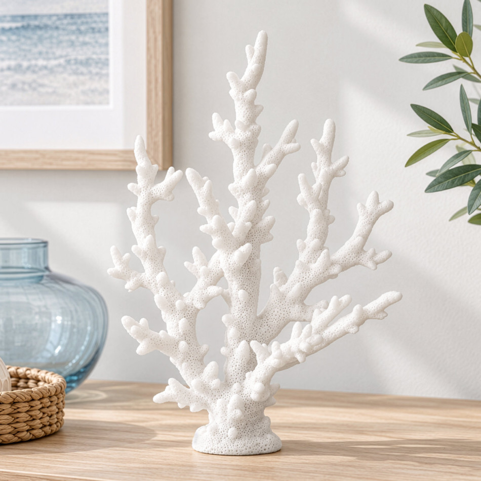 White resin finger coral on a timber sideboard beside a blue glass vase, woven tray and leafy stems