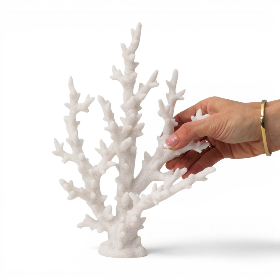 Hand holding white resin finger coral against a white background, showing its branching shape and texture