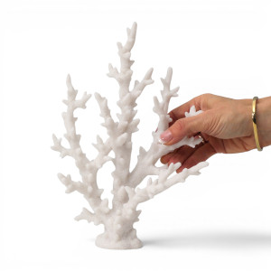 Hand holding white resin finger coral against a white background, showing its branching shape and texture