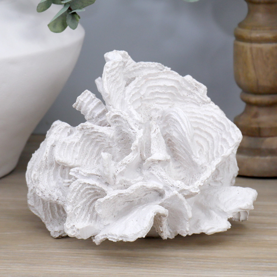 White foliose coral sculpture styled on a wood tabletop with natural candle holders and a white vase.