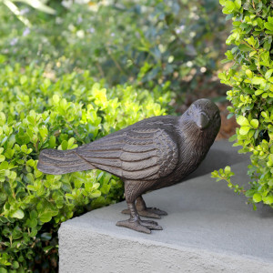 Side view of cast iron crow with layered wing feathers and long tail against a white background