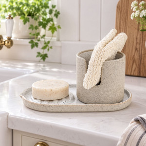 Speckled ceramic soap and sponge holder styled beside a bright kitchen sink