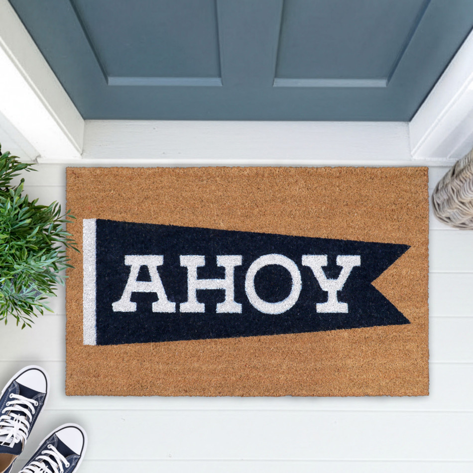 Ahoy nautical coir doormat at a blue-grey door, styled with greenery, a woven basket and navy shoes