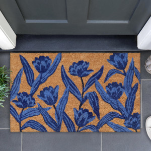 Blue tulip coir doormat on grey tiles beneath a dark front door, with greenery beside it