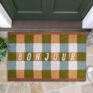 Green and blue-grey gingham coir doormat with white Bonjour lettering on stone paving below a green door