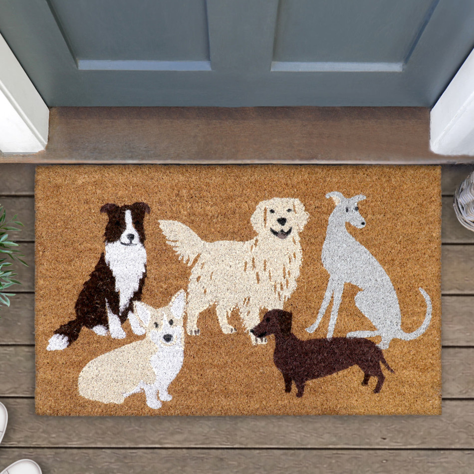 Close-up of a natural coir doormat with five illustrated dogs at a blue-grey door on timber boards