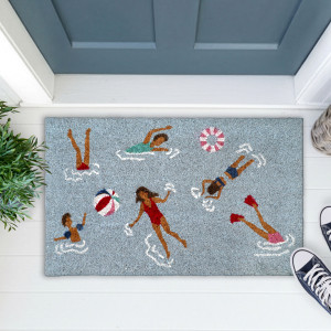 Blue swimmers doormat at a blue-grey door with greenery, a woven basket and navy shoes on white floorboards