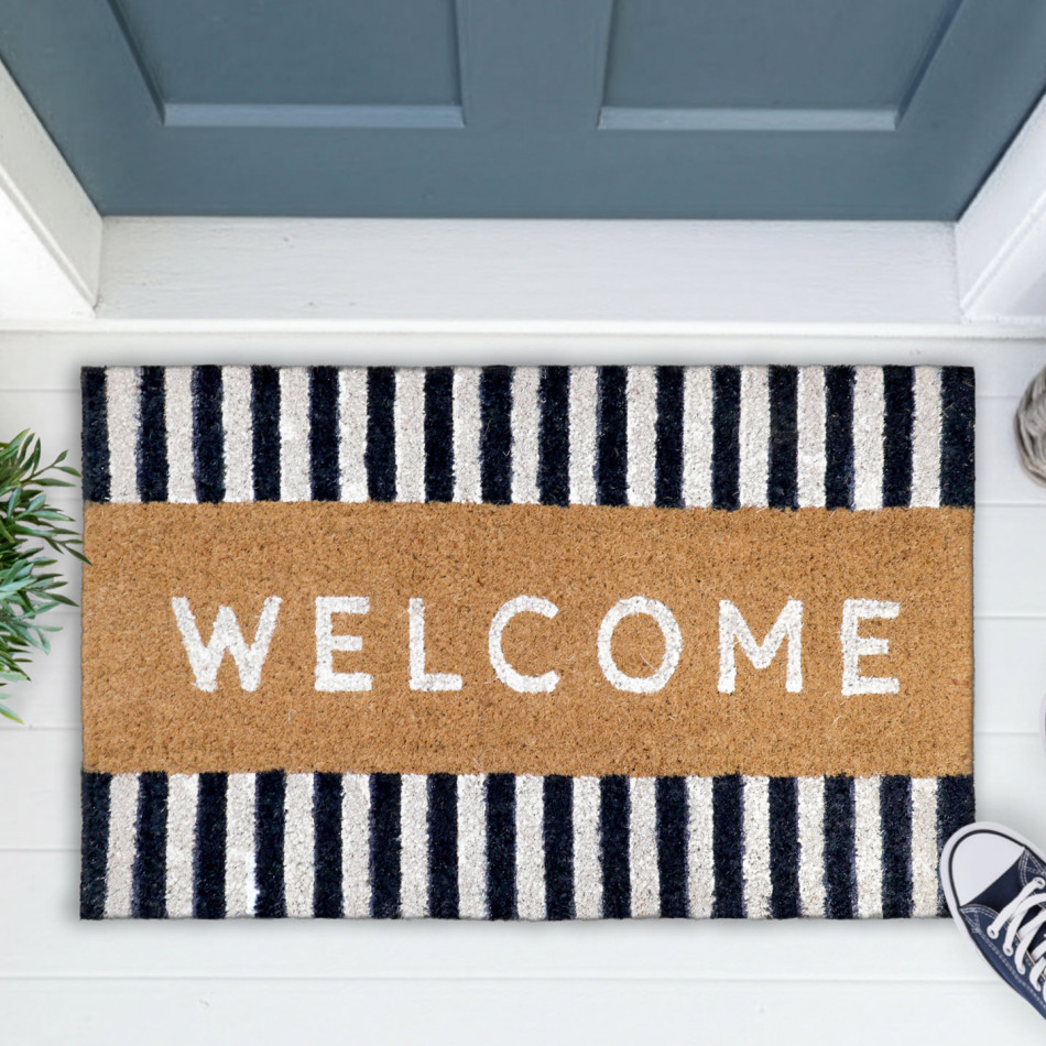 Natural coir welcome doormat with navy-and-white striped borders beside a blue-grey door