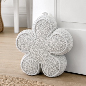 Cream boucle flower door stop holding a white door open on a wood floor