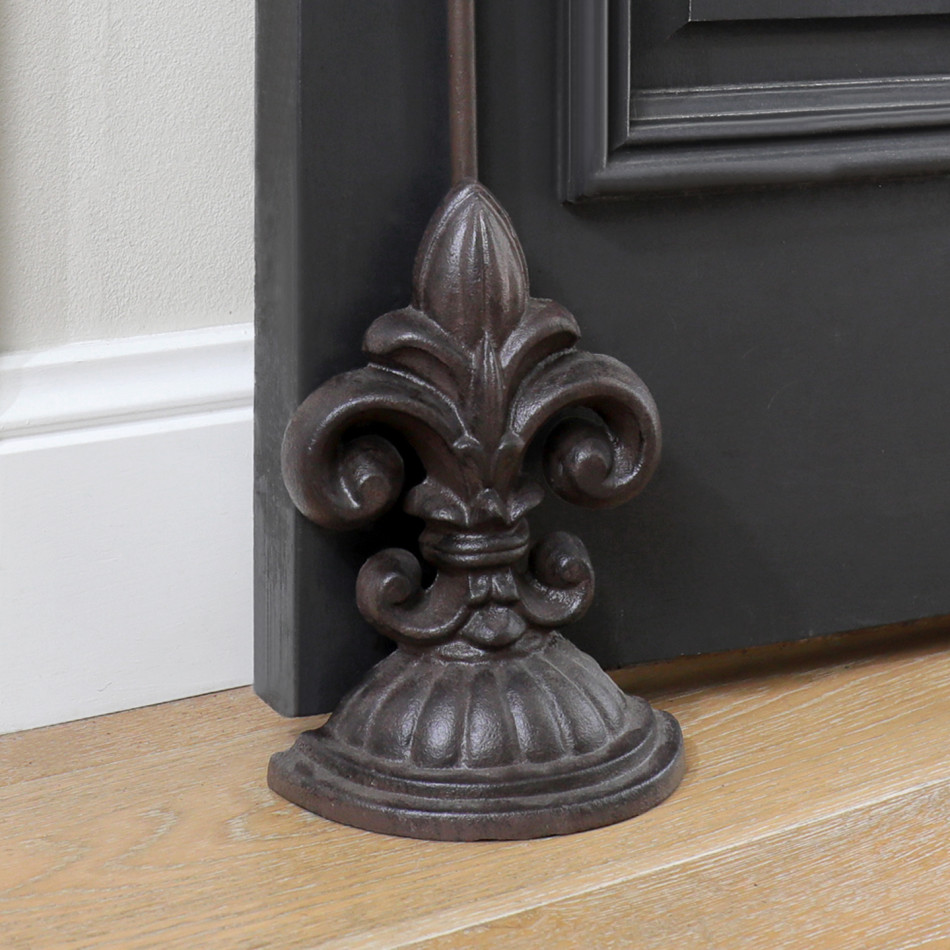 Front view of a dark brown cast iron fleur-de-lis door stop with tall handle and domed base