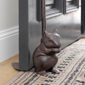 Close up of a tall dark brown cast iron squirrel door wedge with long loop handle