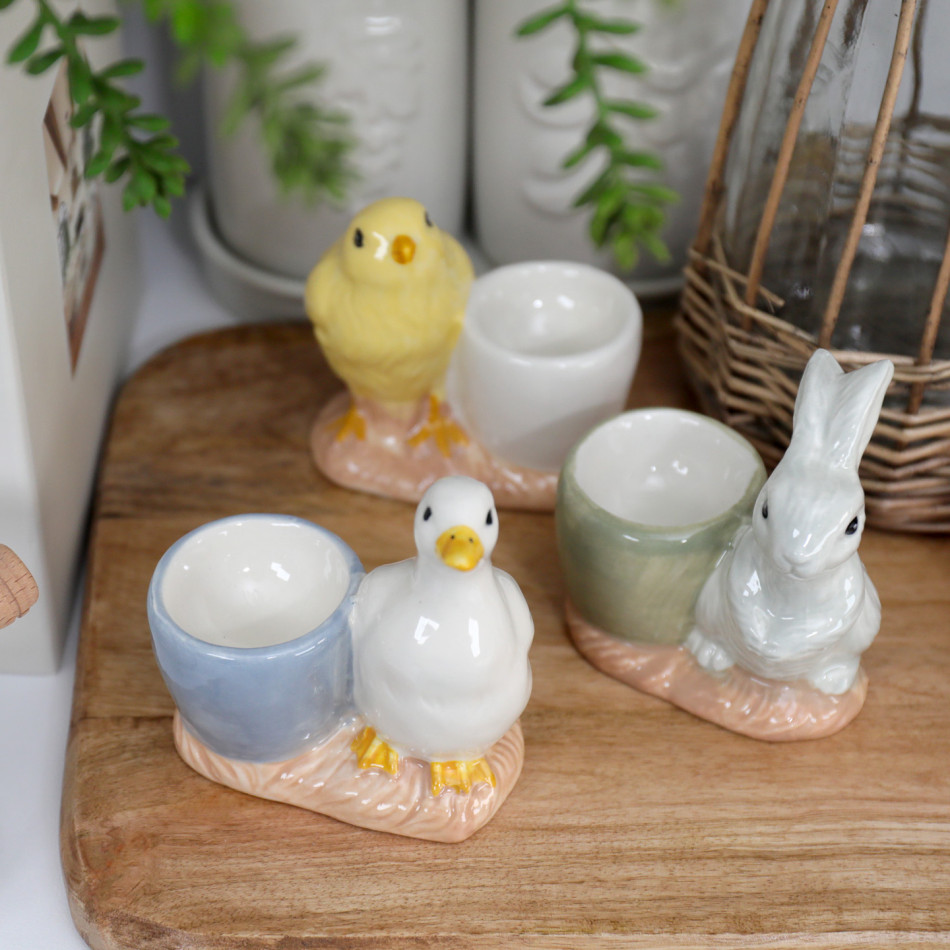 Grey bunny ceramic egg cup displayed with coordinating duck and chick egg cups on a wooden board