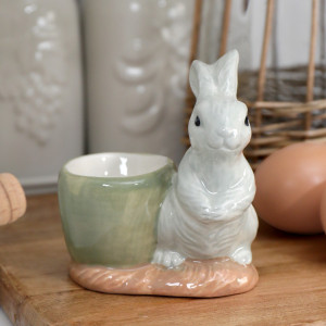 Handpainted grey bunny ceramic egg cup with pale green cup and blush base on a wooden board