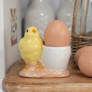 Close-up of the handpainted yellow chick and white ceramic egg cup on its blush base
