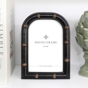 Arched black 4x6 photo frame with faux bamboo detailing and antique gold-toned accents on a white shelf