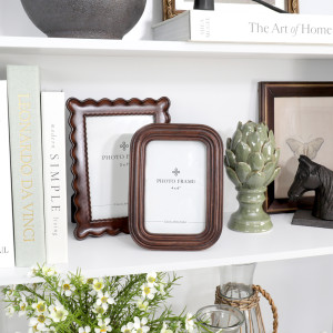 Orleans chestnut 4 x 6 photo frame styled on a white shelf with books, flowers and decorative objects.