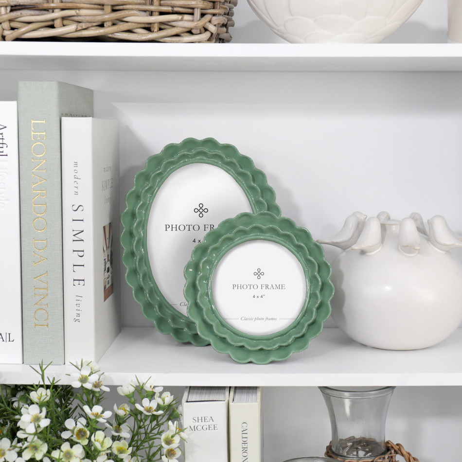 Lillian green scalloped round 4x4 photo frame styled on a white shelf in front of coordinating photo frame.