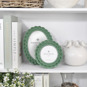 Lillian green scalloped round 4x4 photo frame styled on a white shelf in front of coordinating photo frame.