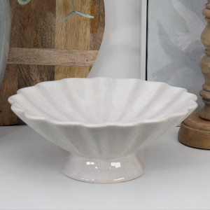 Off-white fluted pedestal fruit bowl with a scalloped rim styled empty beside natural wood décor.
