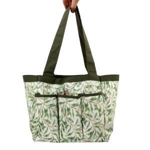 Greenhaven gardener's bag held by its long dark green handles, showing the leaf print and external pockets