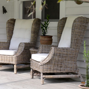 Two Highbury rattan wingback armchairs arranged with a potted plant on a covered verandah
