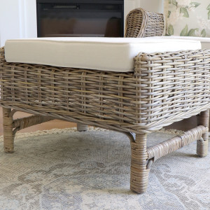Side view of the woven rattan footstool and cream cushion