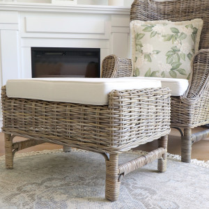 Rattan footstool positioned with the matching armchair beside a fireplace