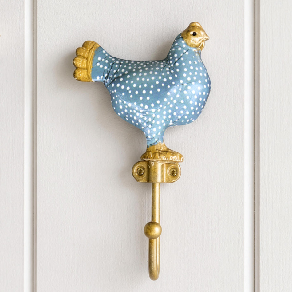 Blue Maisie chicken wall hook with white spots and gold-coloured details mounted on white panelling
