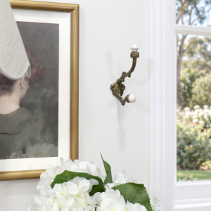 Antique gold and white ceramic wall hook styled with framed artwork and flowers
