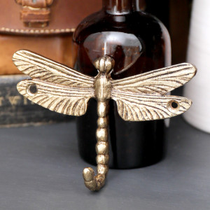 Close-up of a gold metal dragonfly wall hook with textured wings and curled tail