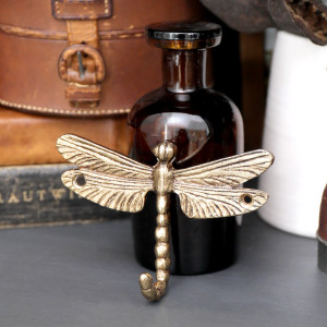 Gold dragonfly wall hook displayed with vintage-style bottles and leather accessories