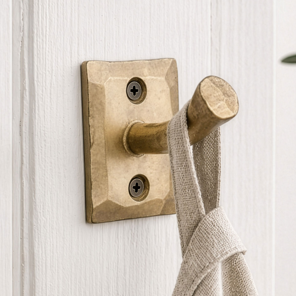 Gold Forge iron nail wall hook mounted on white panelling and holding a natural linen towel