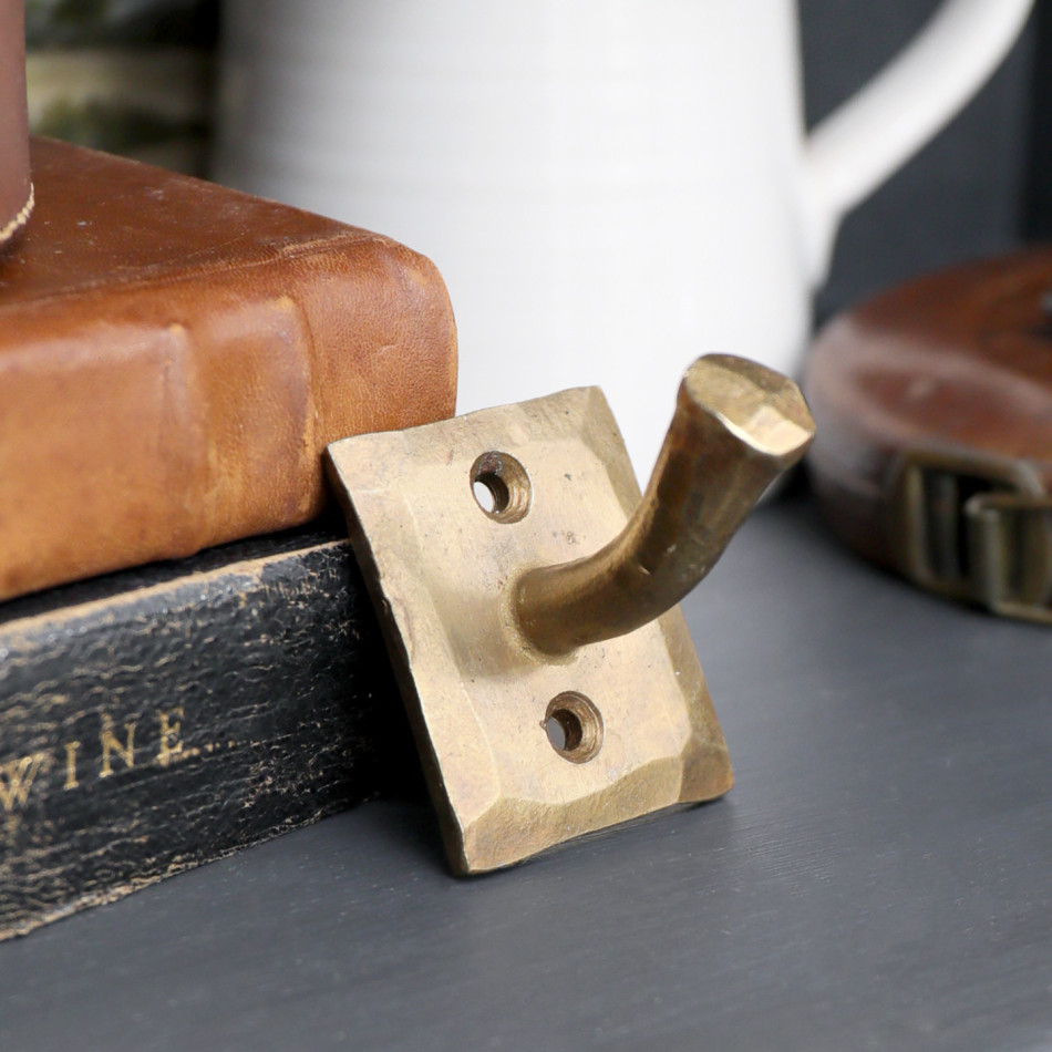 Textured gold nail wall hook styled beside stacked vintage leather boxes