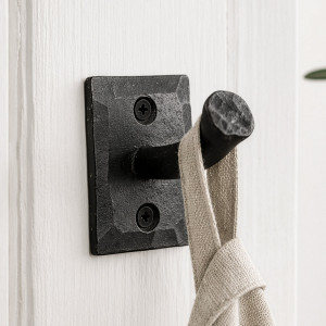Black Forge iron nail wall hook mounted on white panelling with a natural linen towel