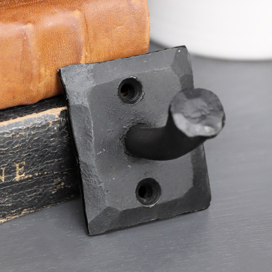Close-up of the textured Black Forge wall hook styled beside vintage leather boxes