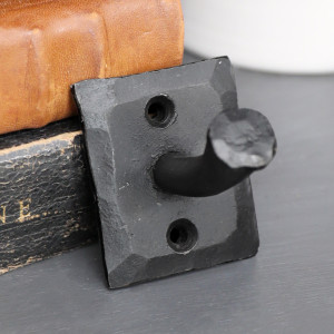 Close-up of the textured Black Forge wall hook styled beside vintage leather boxes
