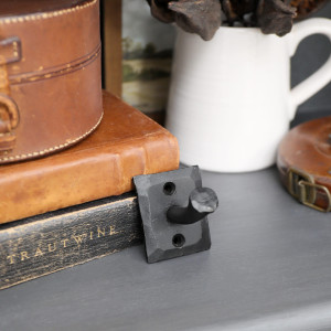 Black nail-inspired iron wall hook displayed with leather boxes and decorative accessories