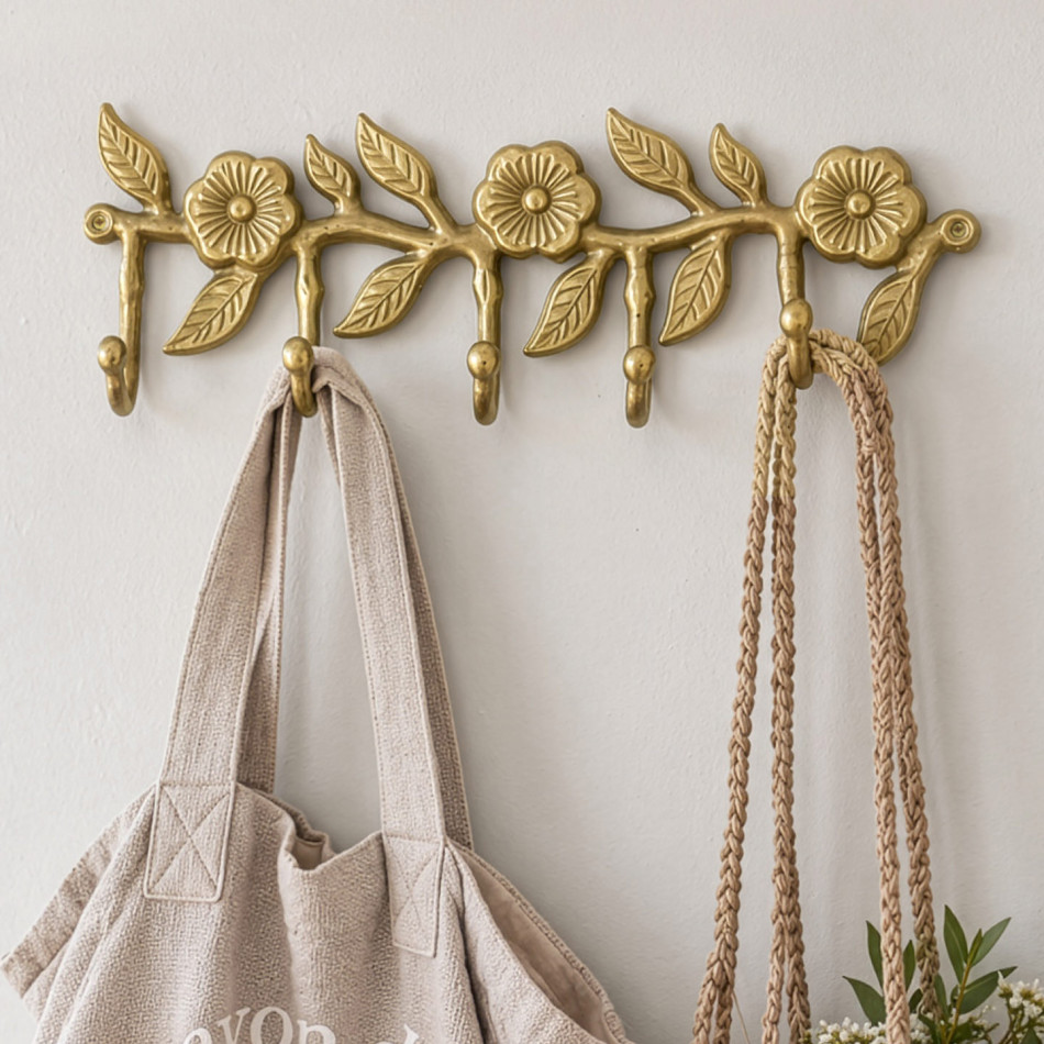 Gold floral wall hook rack with five hooks holding a linen tote and woven plant hanger