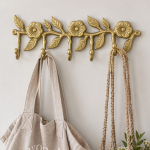 Gold floral wall hook rack with five hooks holding a linen tote and woven plant hanger