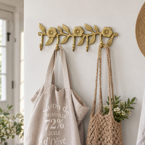 Gold floral five-hook rack mounted in an entryway with two natural woven bags