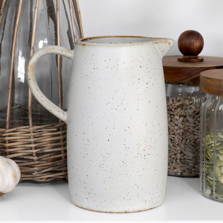 Speckled off-white ceramic milk jug styled beside glass storage jars