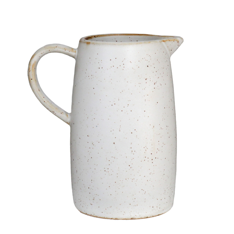 Off-white speckled ceramic milk jug with curved handle and pouring spout on a white background