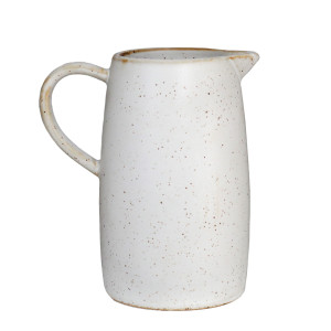 Off-white speckled ceramic milk jug with curved handle and pouring spout on a white background