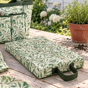 Greenhaven leaf-print knee pad on a timber garden table beside the matching bag and a potted herb