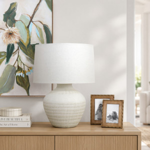 Fernando cream lamp on a timber sideboard with botanical artwork, photo frames, stacked books and a lidded box