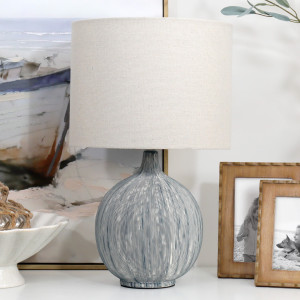 Sandringham textured blue ceramic lamp with linen shade beside wooden photo frames and coastal artwork
